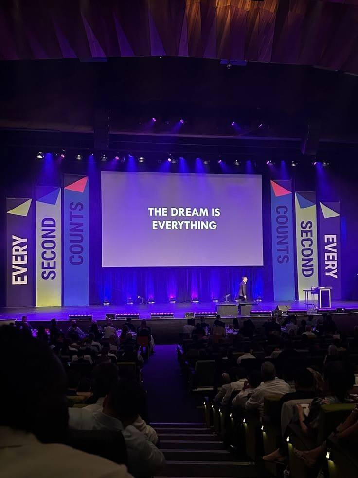 Corporate conference stage with purple lighting and a keynote speaker on stage